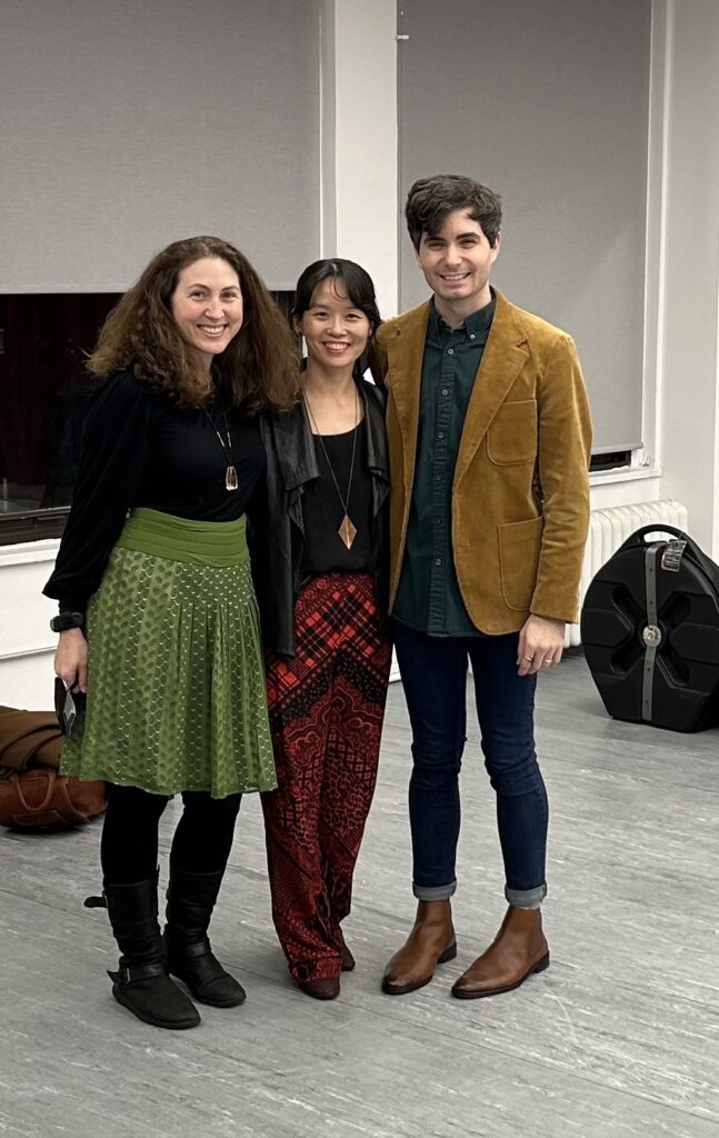 Shoshana, a white woman with shoulder length brown hair in a black shirt and green skirt. Hyeyoung, an Asian woman in a black shirt, black jacket and red patterned pants. Trey, a white man in jeans, a green collared shirt and a tan cordory jacket.